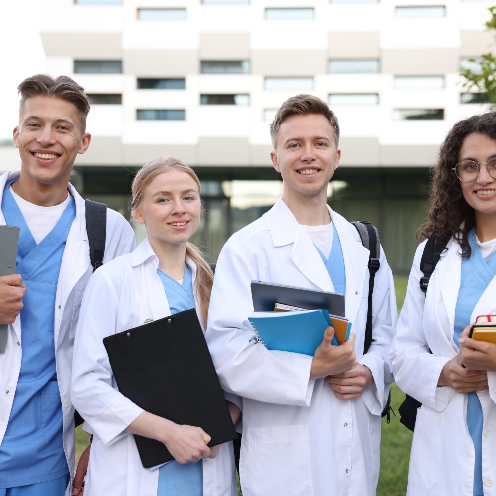 Medical students in uniforms with backpacks and notebooks outdoors, selective focus